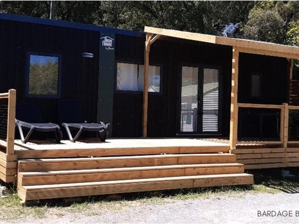 a cabin with two chairs on a deck at Mobil-home confortable 4 personnes - API-1-52-481 in La Mothe-Achard