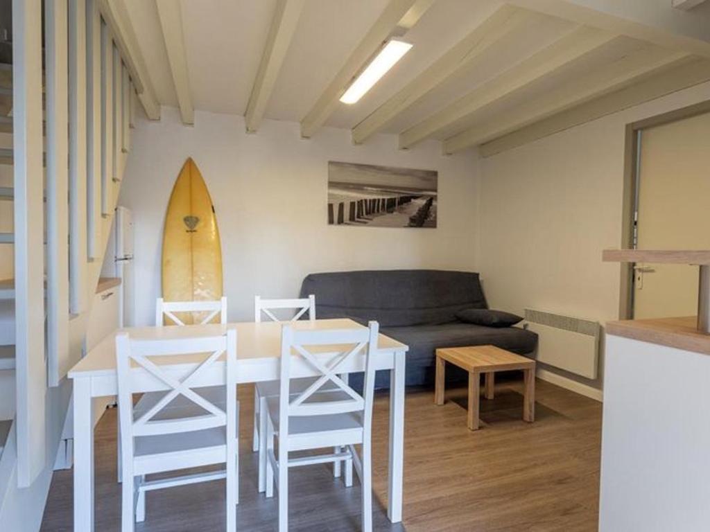 Una sala de estar con una mesa y sillas y un sofá. en Appart 5 pers - Terrasse - Mitoyen - API-1-52-550, en Soustons