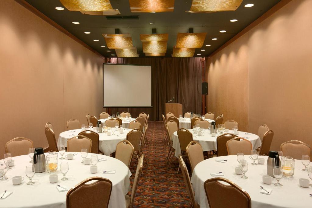einen Konferenzraum mit weißen Tischen und Stühlen und einem Bildschirm in der Unterkunft Harrah&#39;s Casino &amp; Hotel Council Bluffs in Council Bluffs