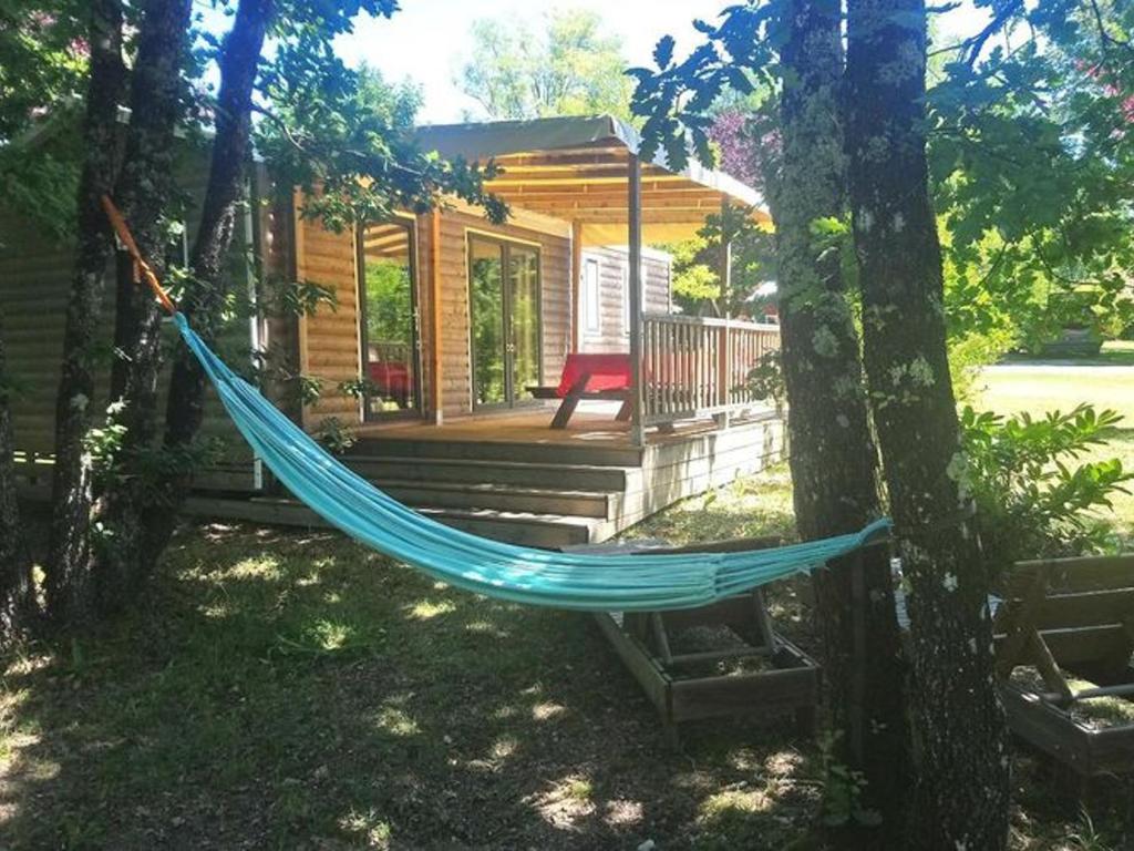 - un hamac en face d'une cabane en rondins dans l'établissement Mobil home spacieux avec terrasse à Dévillac - API-1-52-234, à Dévillac