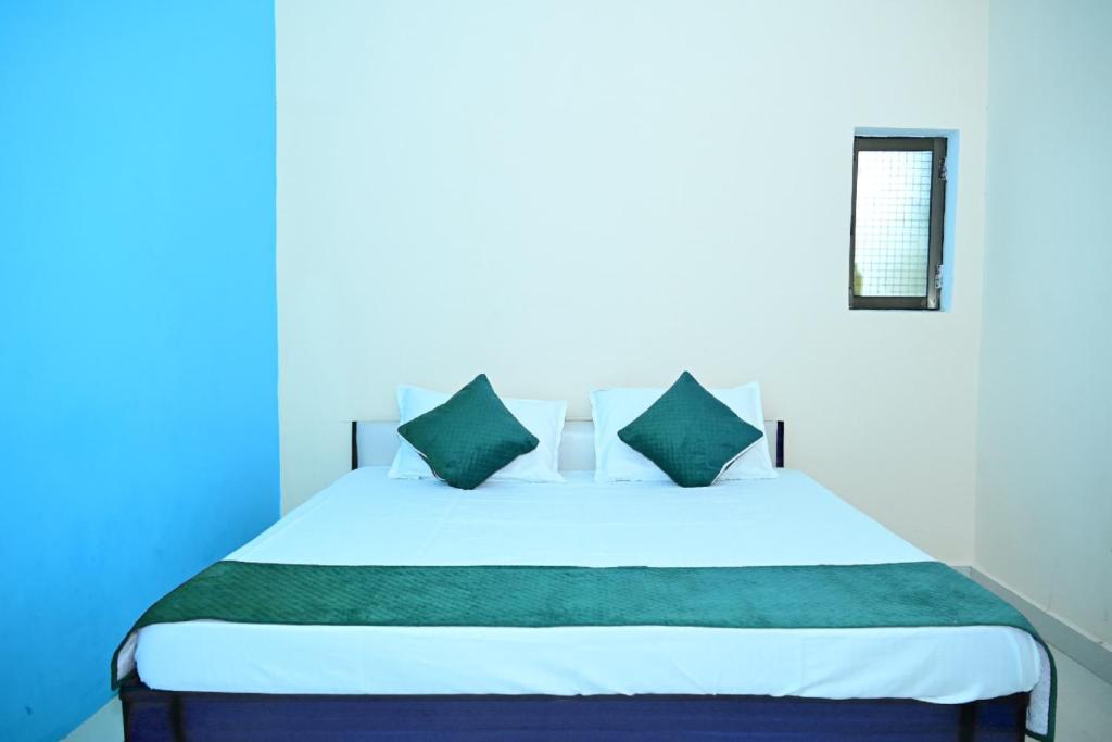 a bedroom with a white bed with green pillows at Aashirwad paying guest house in Ayodhya