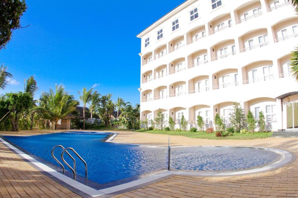 un hôtel avec une piscine devant un bâtiment dans l'établissement Hoa Binh - Rach Gia Resort, à Rạch Giá