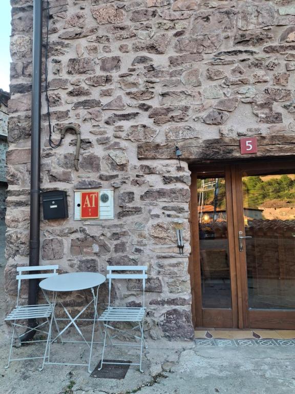 a table and two chairs in front of a stone building at Casa Sorianna in Montenegro de Cameros