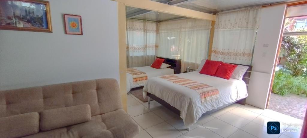 a bedroom with two beds and a couch at Hostal el Parque Tababela in Tababela