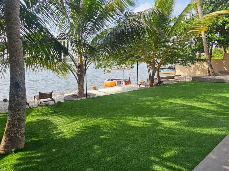 Un parque con palmeras y un banco y agua. en Aqua Leisure Resort Bentota, en Bentota