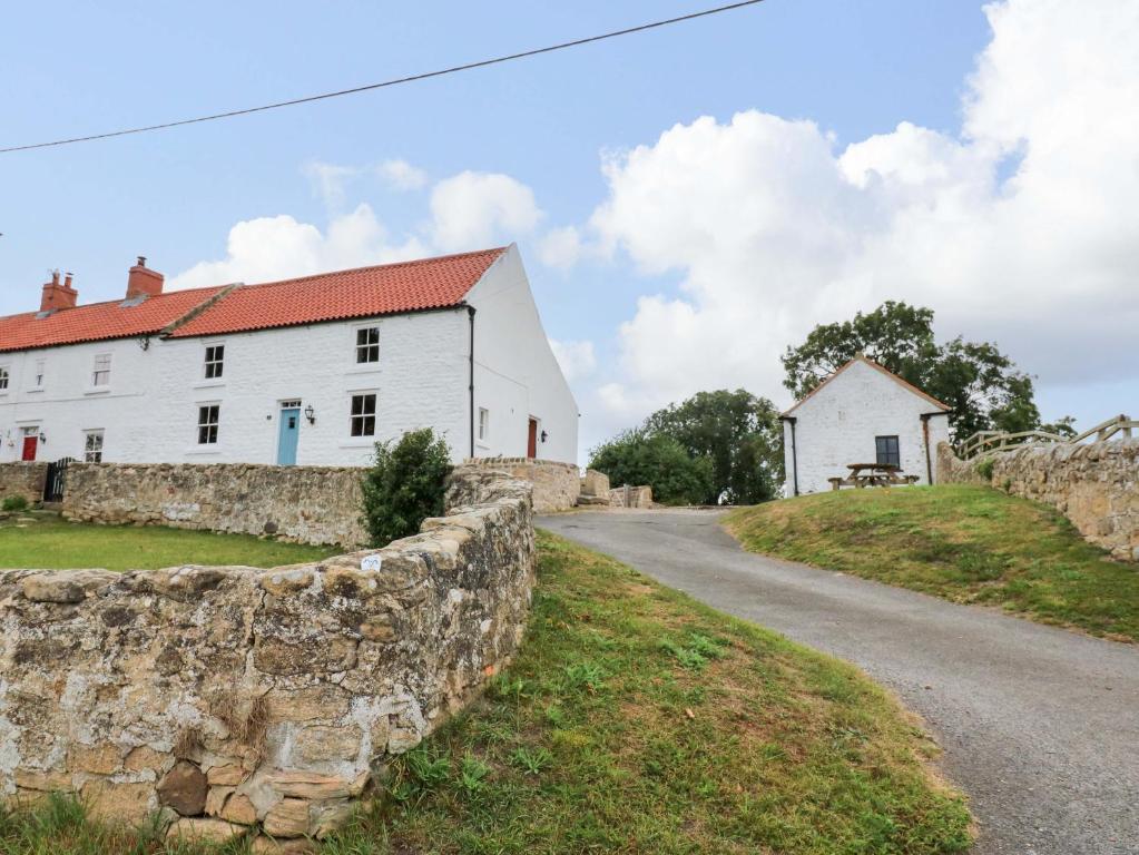 a stone wall next to a white house and a road at Peace Cottage in Darlington