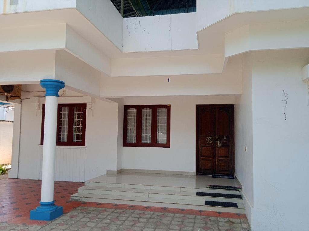 a white building with a column and a door at Ocean blue home stay in Pallipuram