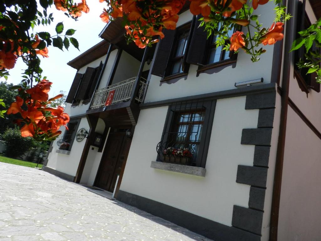 a white building with black windows and orange flowers at Aslibey Konaği - Adults Only in Sapanca