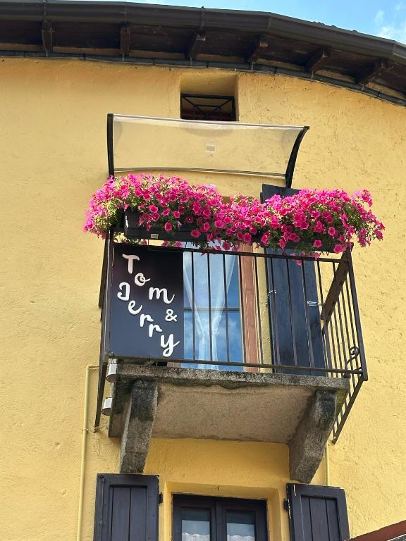 a balcony with pink flowers and a sign on it at Tom e Jerry in Lierna