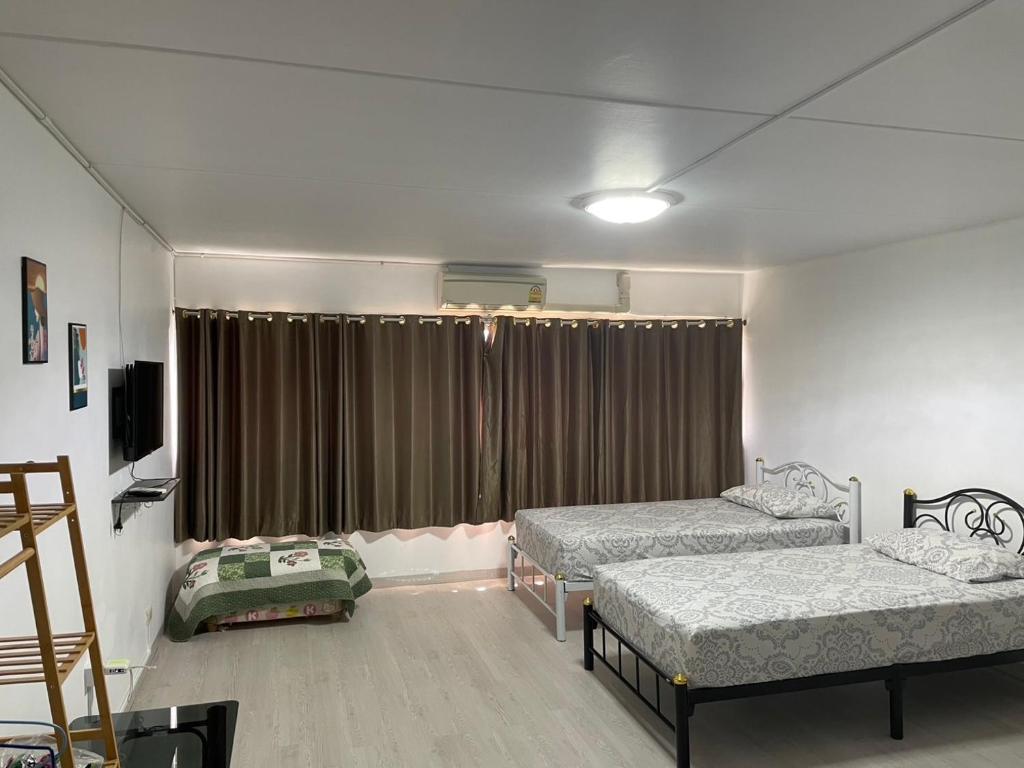 a room with two beds and a window with curtains at Dailyroom C3,C4by Anna in Nonthaburi