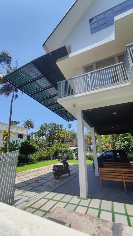 ein Roller, der unter einem Haus mit Terrasse geparkt ist in der Unterkunft Nishwas homes in Kochi