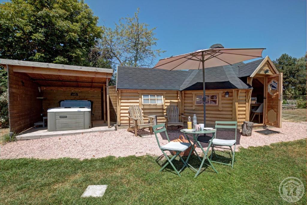 a cabin with a table and chairs and an umbrella at Les Cabanes du Grand Nord in Pradines