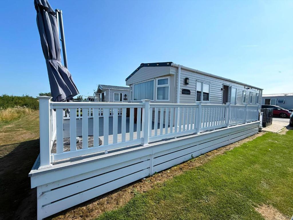 a house with a white fence on a yard at Stunning Caravan With Wifi & Decking At St Osyth Beach In Essex Ref 28007Sv in Clacton-on-Sea