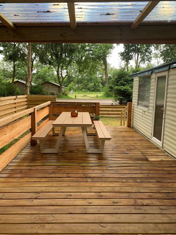 a wooden deck with a picnic table on it at Heerlijke ruime stacaravan met overdekte veranda en omheinde tuin ''Casa Elvina'' in Eext