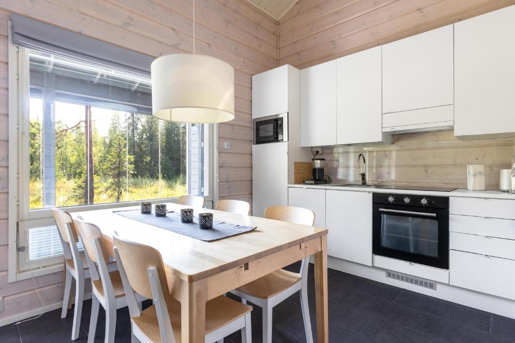 a kitchen with a wooden table and chairs in a room at Tunturihovi A in Äkäslompolo