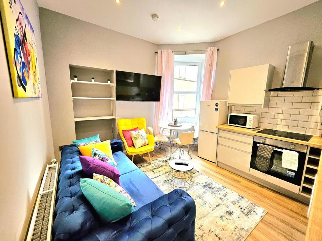 a living room with a blue couch and a kitchen at Sensational Stay- Fountainbridge in Edinburgh