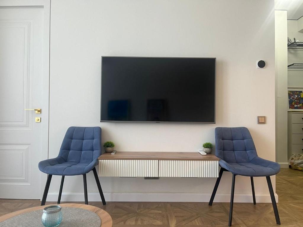 2 sillas azules en la sala de estar con TV en City House, en Tiflis