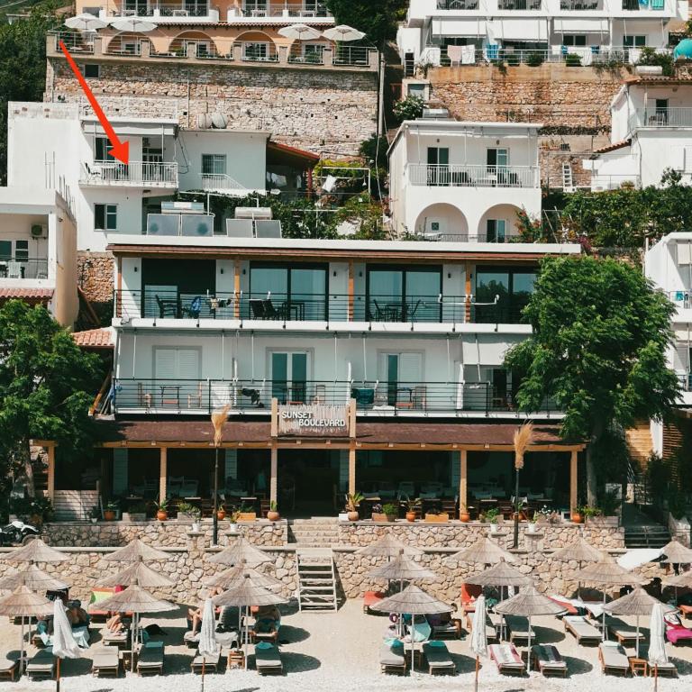 a building with tables and umbrellas in front of it at Sunset Boulevard Rooms in Qeparo