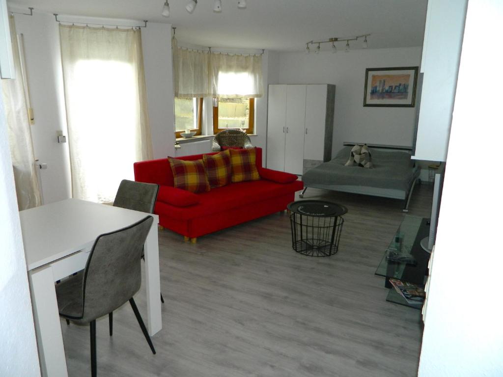 ホルツガーリンゲンにあるHelle 45 qm Einliegerwohnungの赤いソファとテーブルのあるリビングルーム