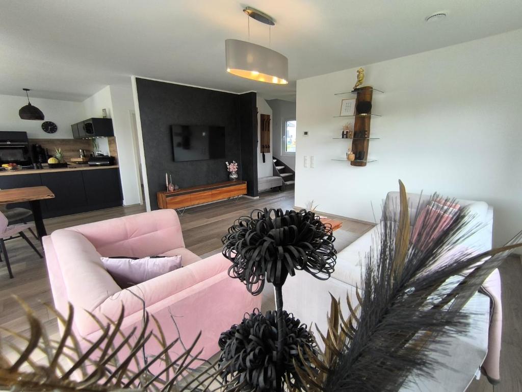 a living room with a pink couch and a table at VILLA VULKANEIFEL -modern -familienfreundlich -Terrasse -Doppelgarage -ruhiger Lage in Darscheid