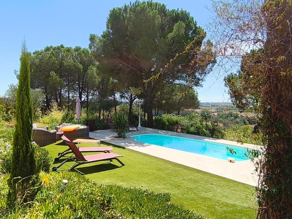 a pool in a yard with two lounge chairs at "Le Mas" Les jardins de Tourneige in Maraussan