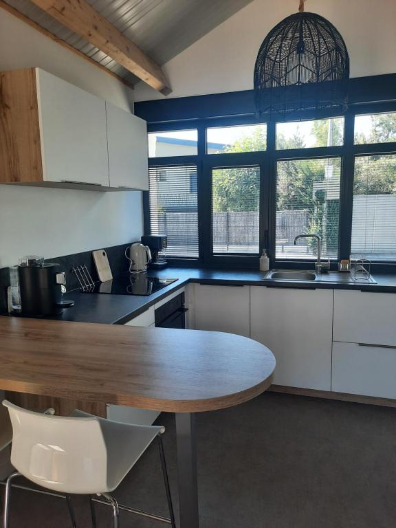 una cucina con tavolo in legno e alcune finestre di Le cottage , logement individuel de plain pied a Villeneuve d'Ascq