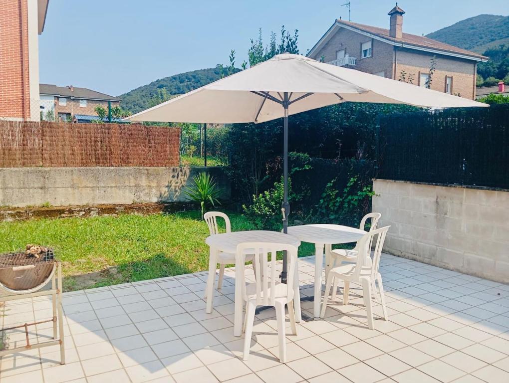 a table and chairs under an umbrella on a patio at Familiar bajo con jardín en Gibaja in Gibaja