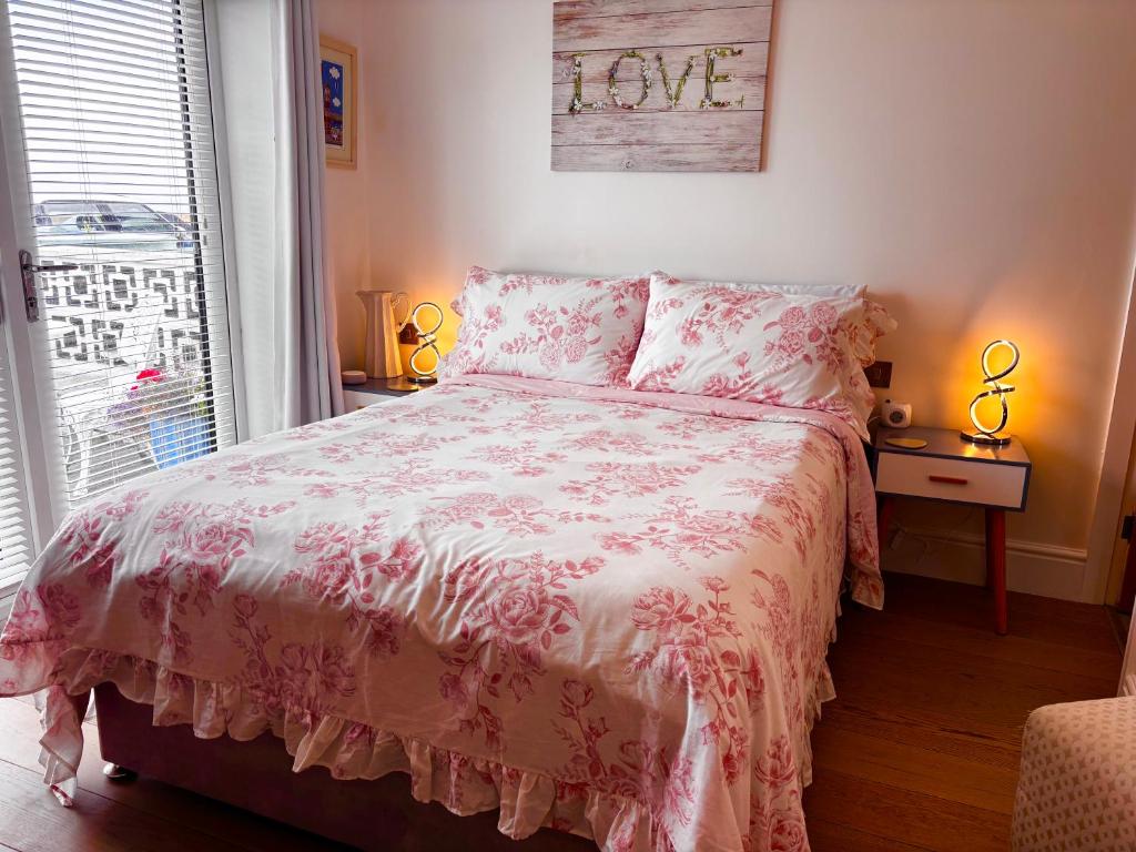 a bedroom with a bed with a pink bedspread and a window at Sunsets, Sandylands Prom Morecambe in Morecambe
