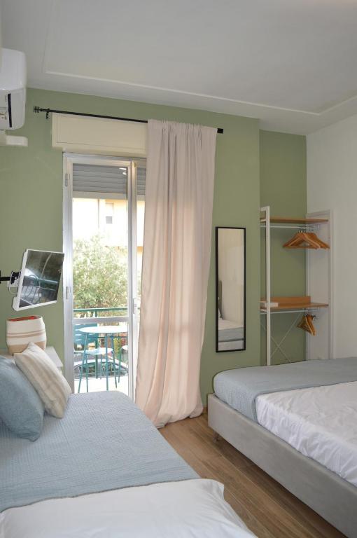 a bedroom with two beds and a sliding glass door at Magic Home in Ceriale