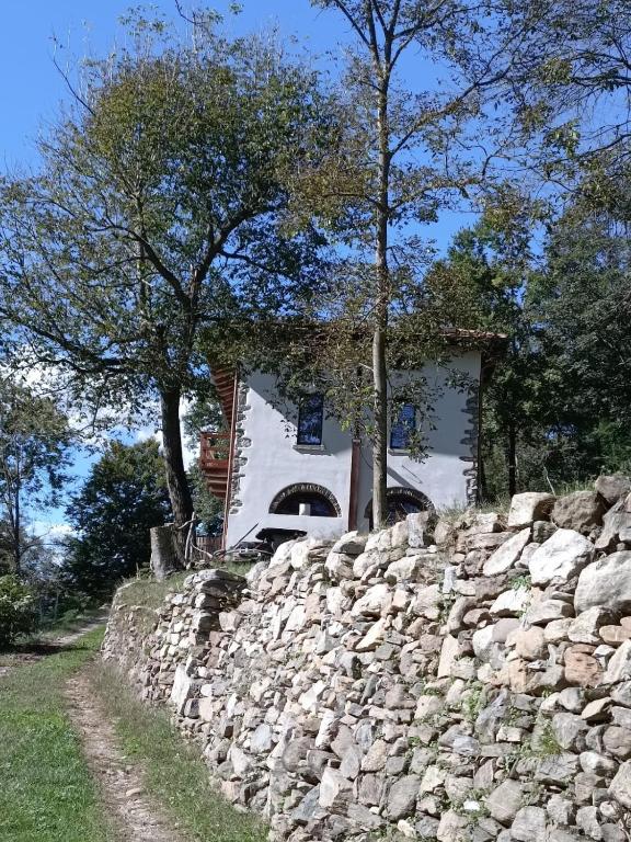 a house behind a stone wall next to a tree at Country Cottage by LePigne World in Ameno