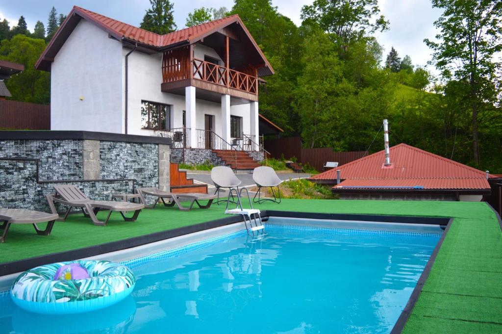 a house with a swimming pool in front of a house at Villagoria котедж з басейнами і джакузі in Slavske