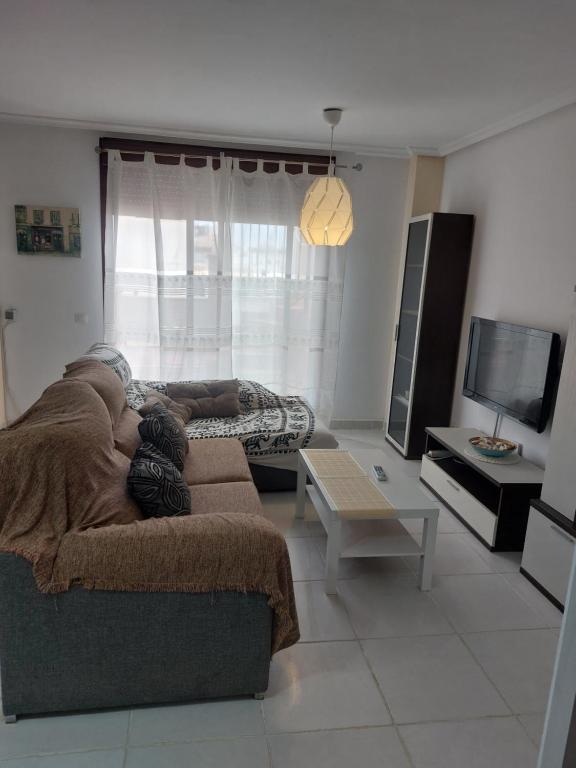 una sala de estar con un sofá y un televisor en Apartamento playas de Vera, en Vera