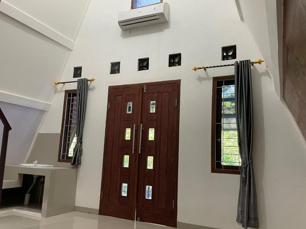 Zimmer mit 2 Türen und einem TV an der Wand in der Unterkunft Villa Airunika in Bandar Lampung