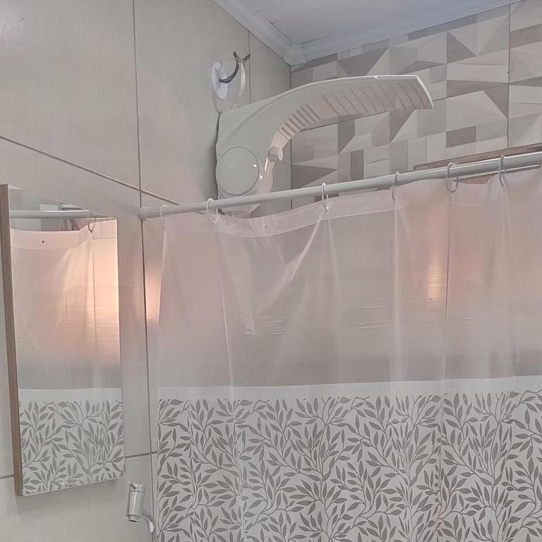 a shower with a glass door with a shower curtain at Guest House in Petrópolis in Petrópolis