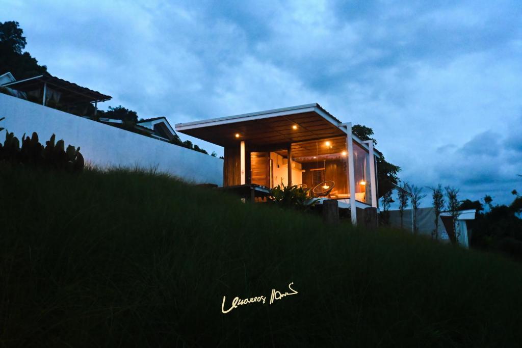 a house on top of a hill at night at บ้านละอองฟ้า1 แอร์ ม่อนแจ่ม วิวดอยหลวงเชียงดาว in Mon Jam