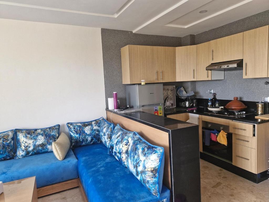 a living room with a blue couch in a kitchen at Bel appartement pour location in O Ben Slimane