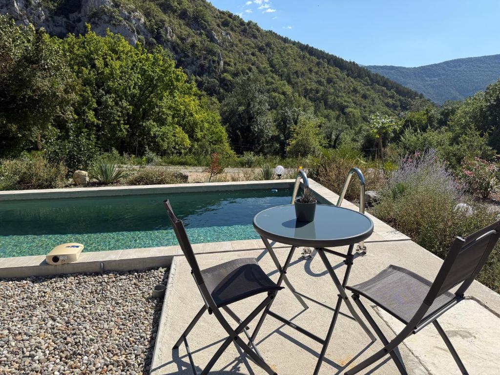 - une table et deux chaises à côté de la piscine dans l'établissement Gites Les Rochers de Plaisians, à Plaisians