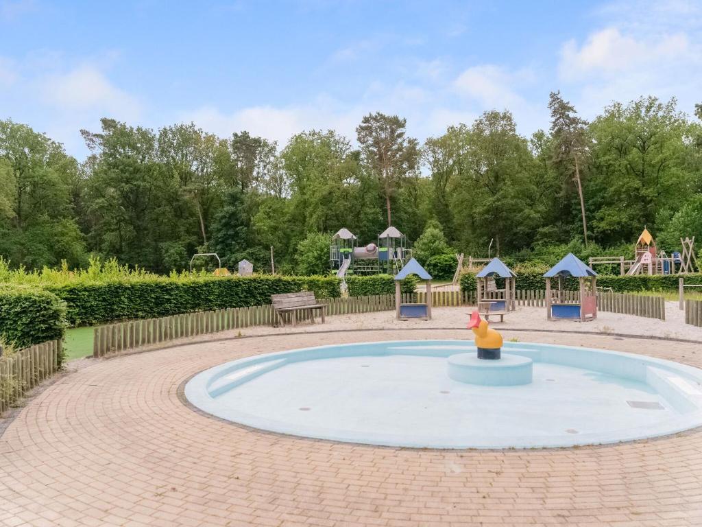 a small pool in a park with a playground at chalet in the woods with pool in Vledder