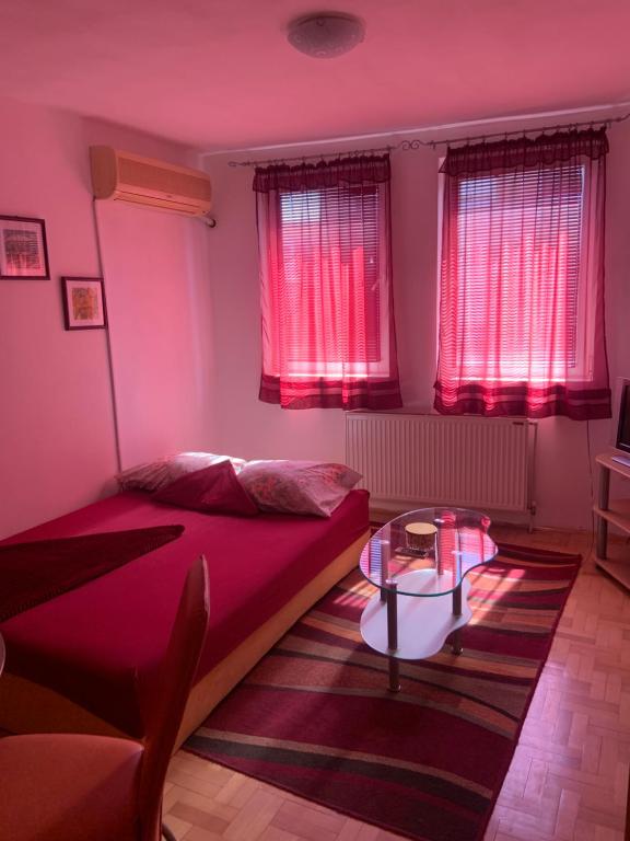 a bedroom with red curtains and a bed and a table at Urban Hideout City Center Nis in Niš