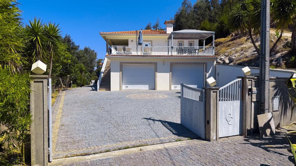 una casa con dos puertas de garaje y un camino de entrada en Cerca do casal, en Santo Tirso
