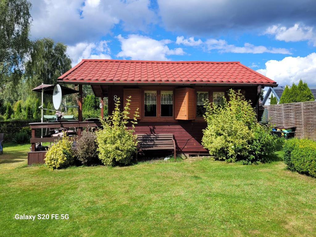 a small house with a red roof on a yard at Domek letniskowy Iwonka in Zbychowo
