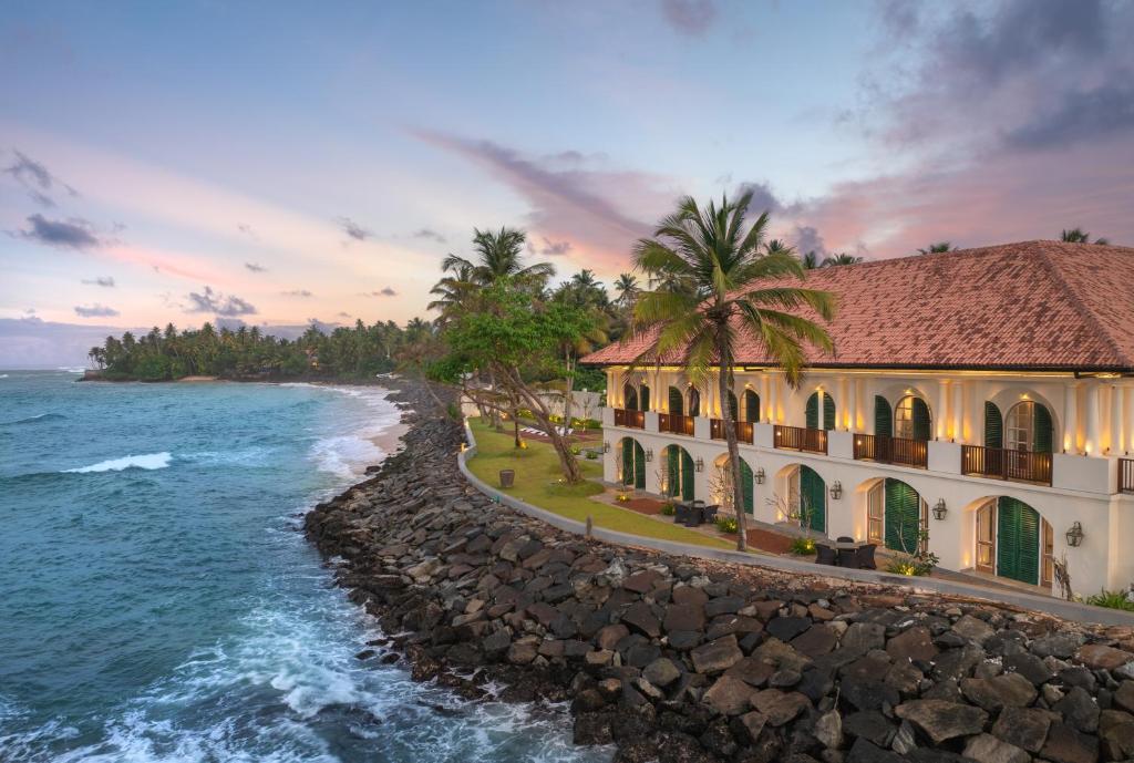 a building on the shore of the ocean at The Flute Mansion in Talpe