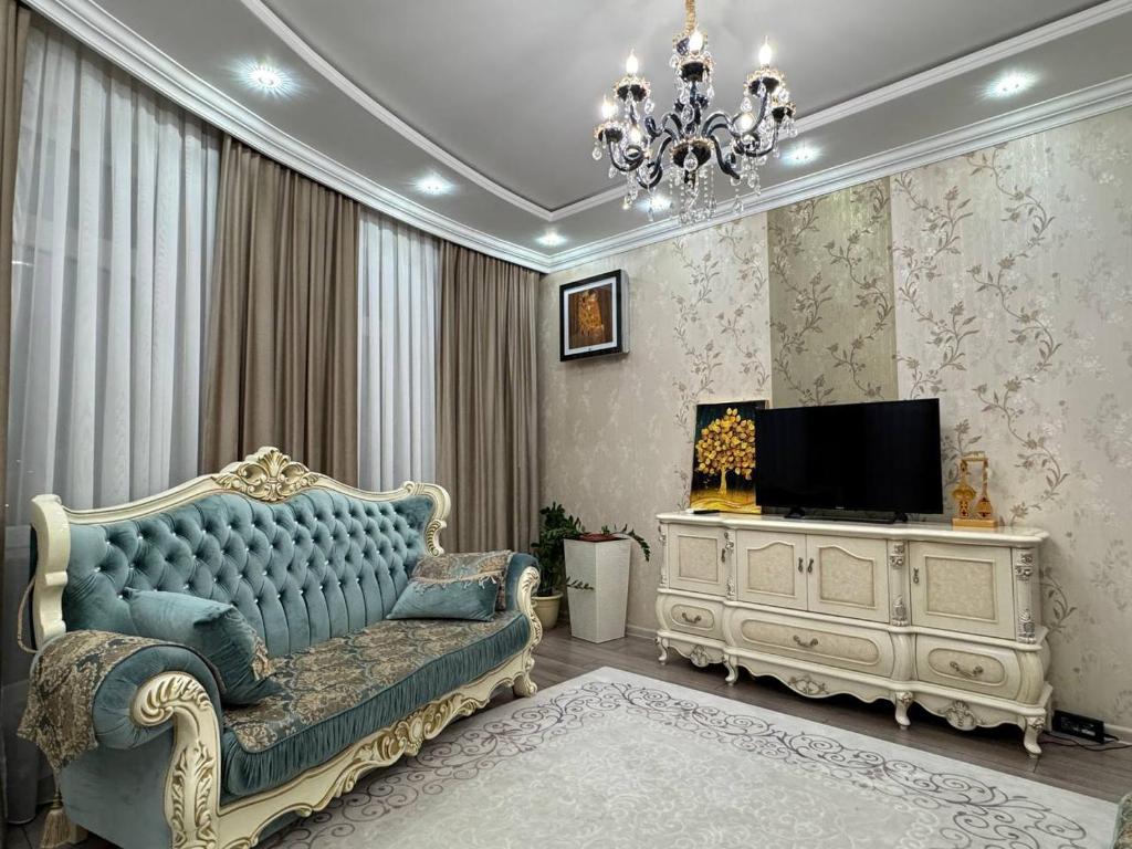 a living room with a blue couch and a tv at Promenade EXPO in Astana
