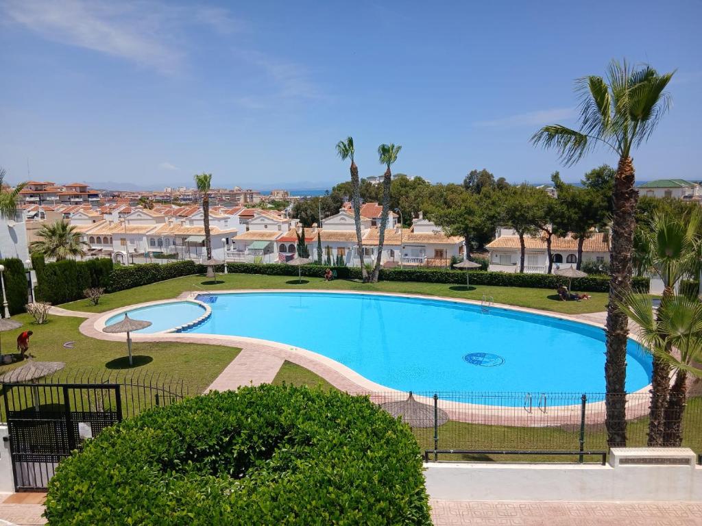a large swimming pool in a resort with palm trees at Apartament La Mata -Maya Bungalow in Torrevieja