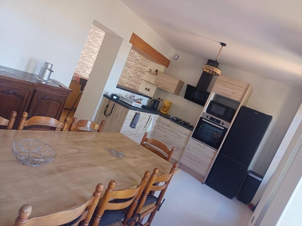 a kitchen and dining room with a wooden table and chairs at La petite Maison in Vézézoux