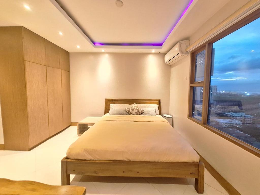 a bedroom with a bed and a large window at BREATHTAKING BAY AND CITY VIEWS- 1-5 BR Luxury and Superior Condos with, Balcony, Pool, Netflix & Gym- Housekeeping Available - in Manila