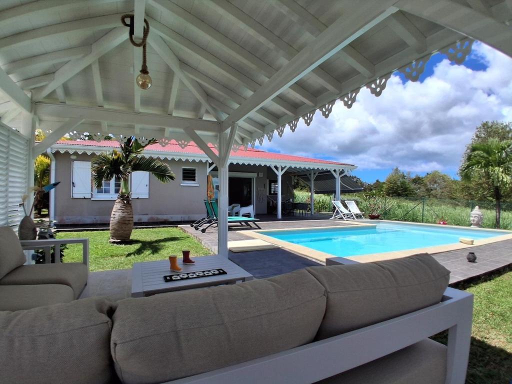 a patio with a couch and a swimming pool at Belle Villa 3 chambres piscine Rivière Salée in Rivière-Salée