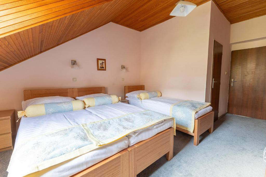 two beds in a bedroom with wooden ceilings at Hotel Wilhelm in Prague