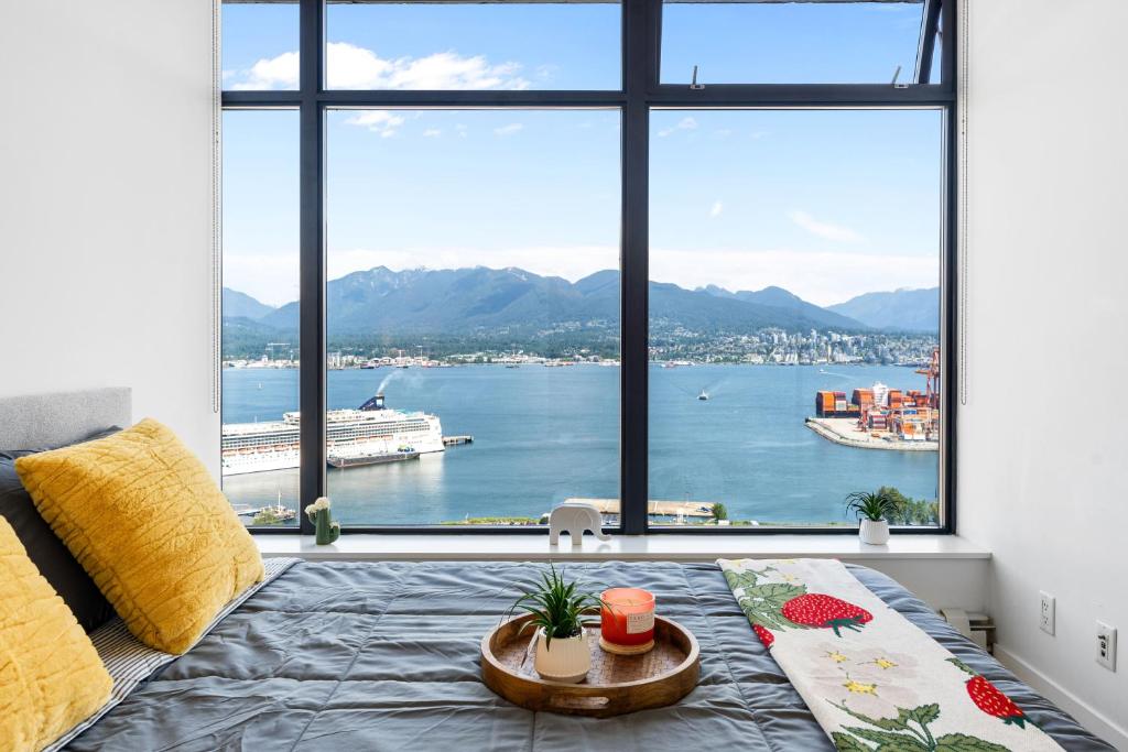 a bedroom with a large window with a view of the water at Stylish 2BR Loft in Historic Gastown with Mountain Views in Vancouver