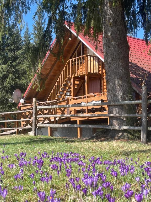a log cabin with a tree and purple flowers at Садиба Урочище Луг in Vorokhta